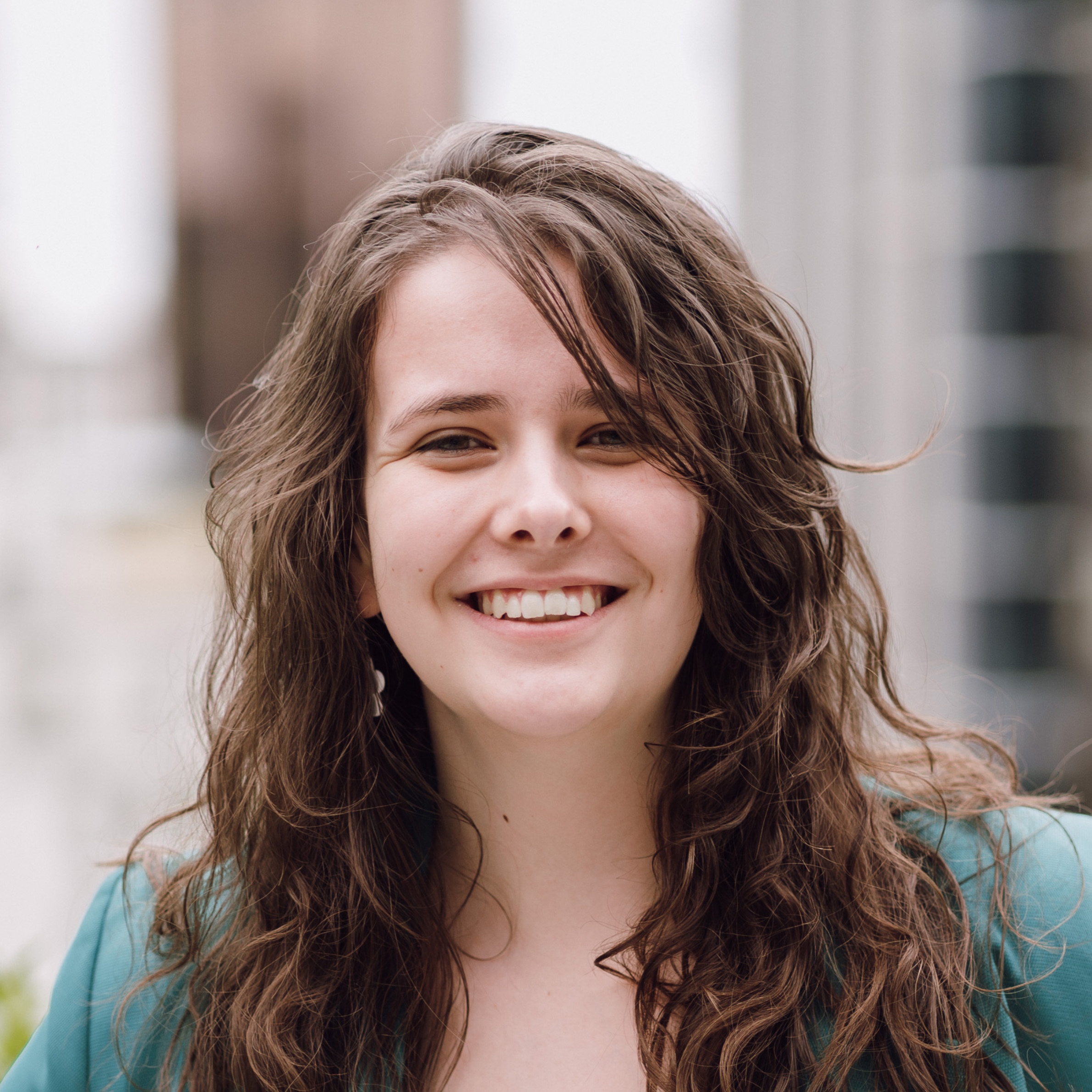 Hope is a young, white woman with long brown hair wearing a green jacket. She is smiling at the camera.