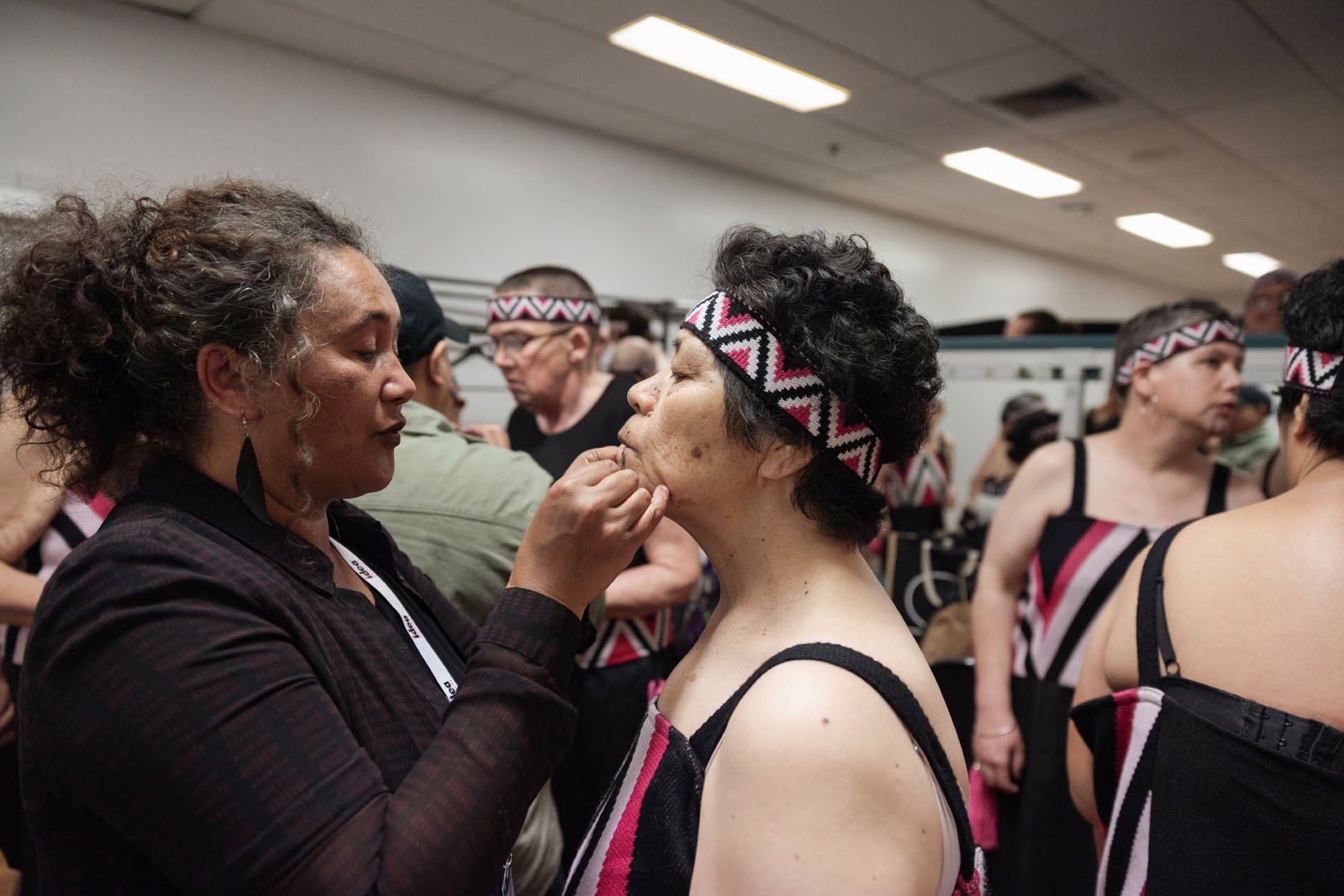 A kaihaka is having a stick-on ta moko applied to her chin.