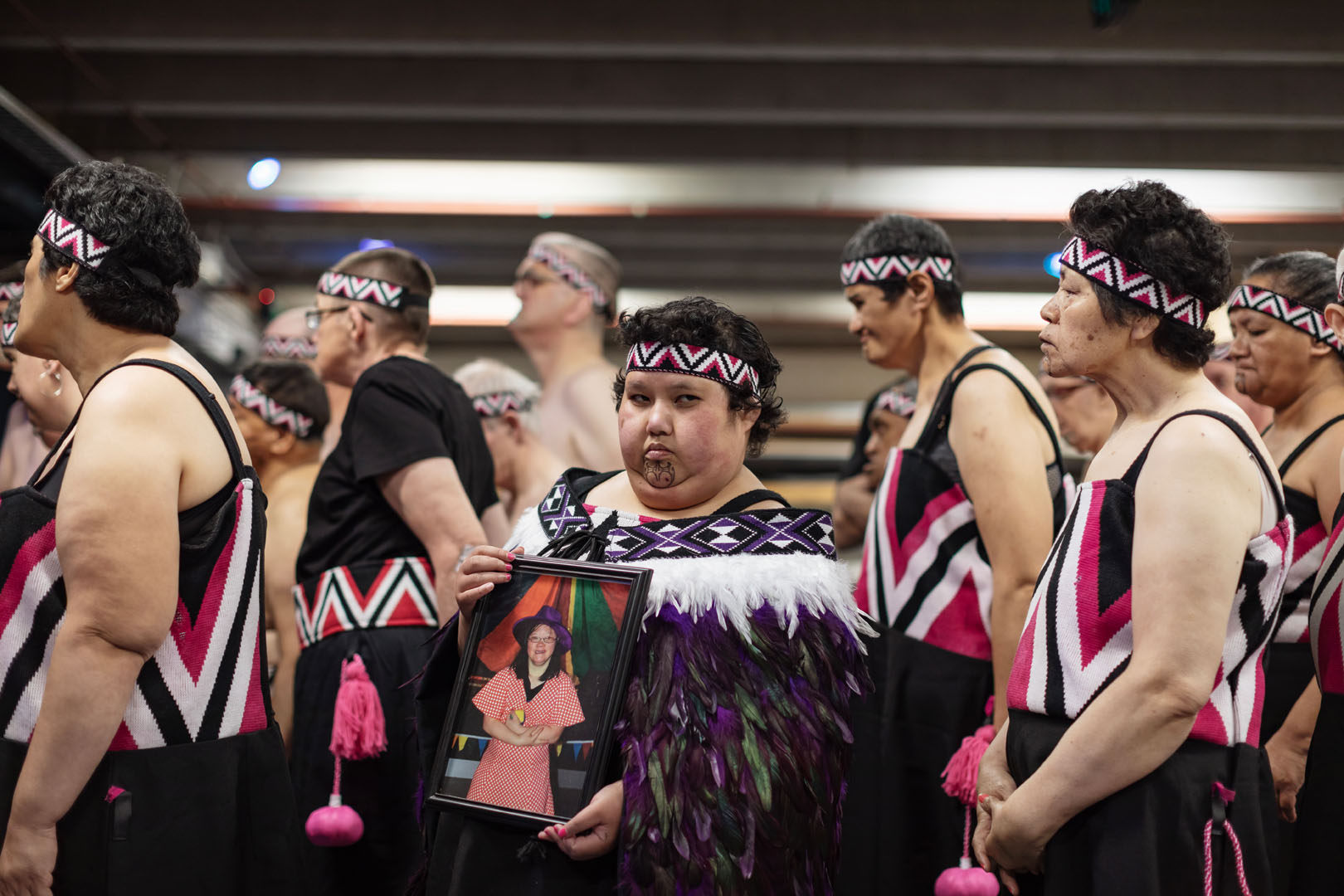 The rōpū members line up, with one kaihaka holding a photograph of Lena Zhang Harrap.