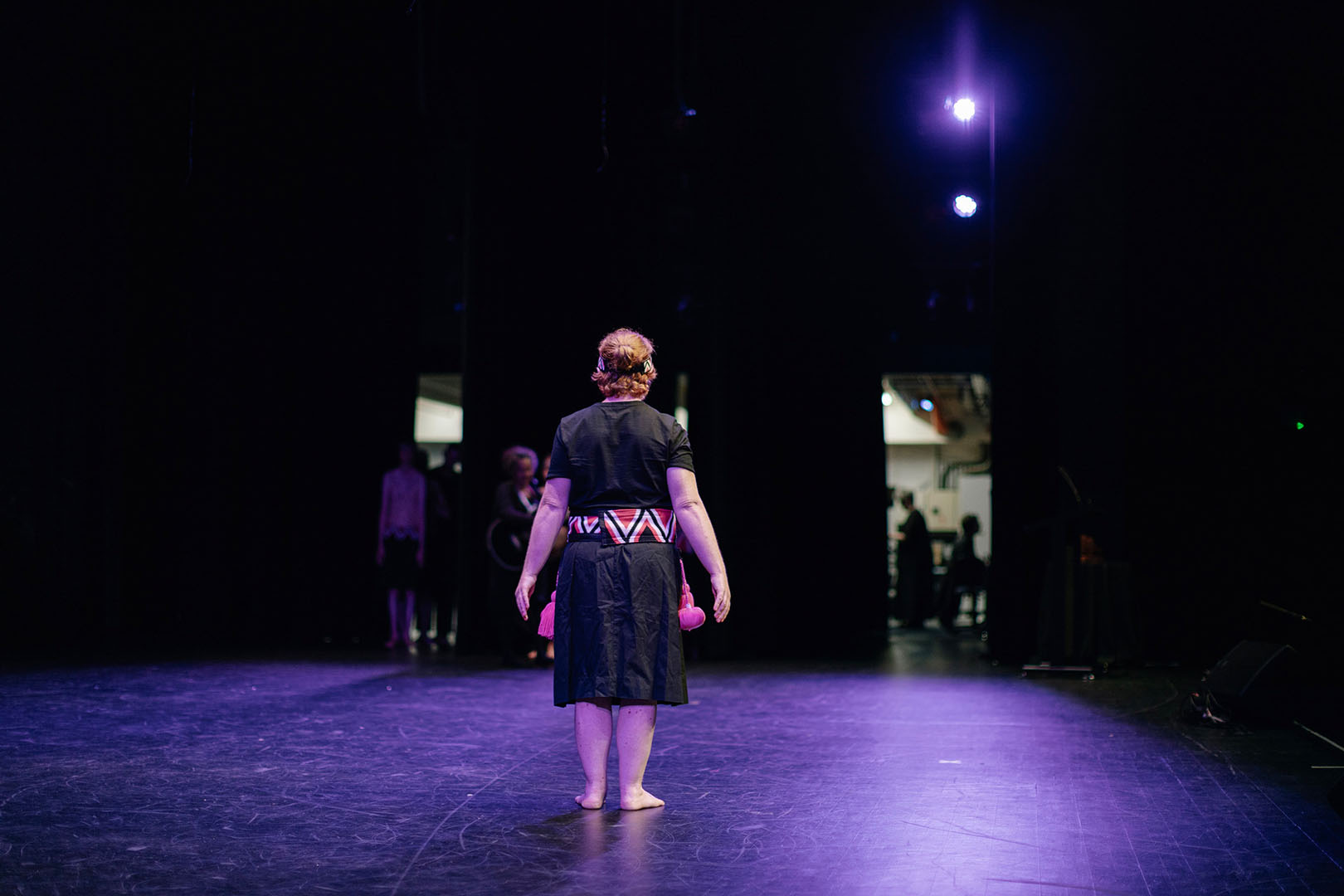 A rōpū member stands alone on a stage underneath purple lights. 