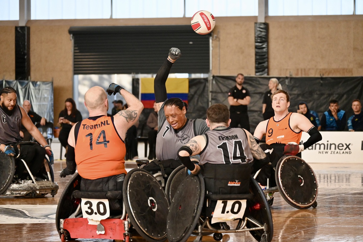 Wheelchair rugby athletes from New Zealand and the Netherlands try grab a ball in the air.