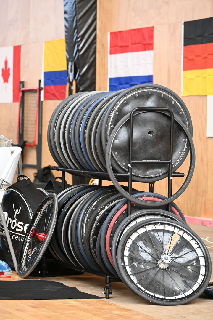 A black metal rack holds spare wheelchair tyres.