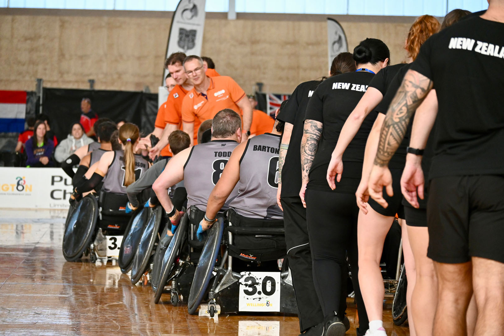 Athletes and the support crews from New Zealand and the Netherlands line up to shake hands after a match.