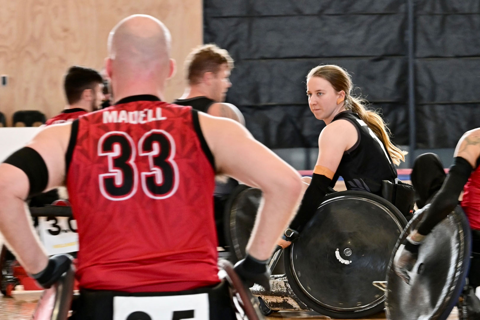 Jacinta Richardson plays wheelchair rugby and moves across the court between two Canadian players.