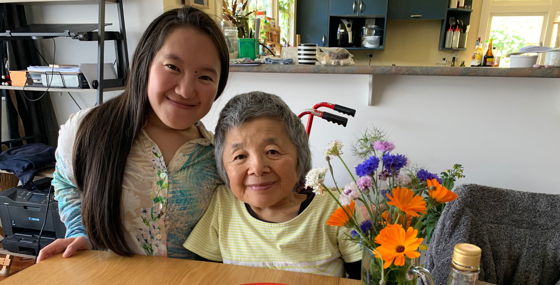 Umi and Yuho are pictured at a wooden table with bright, colourful flowers.
