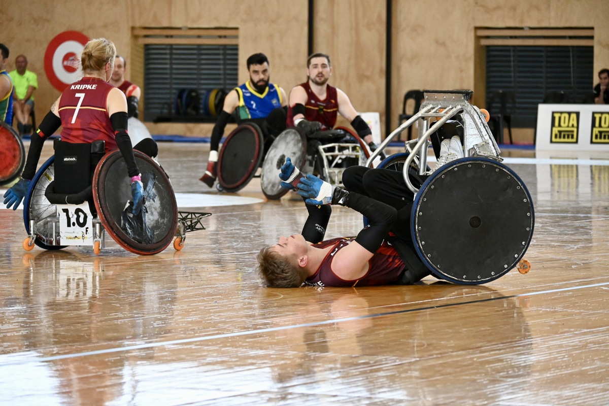A Canadian wheelchair rugby is tipped backwards in his wheelchair on the court.
