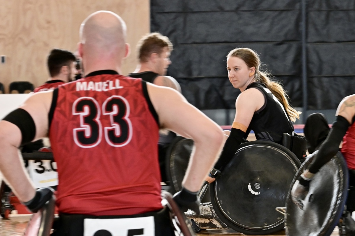 Jacinta Richardson plays wheelchair rugby and moves across the court between two Canadian players.