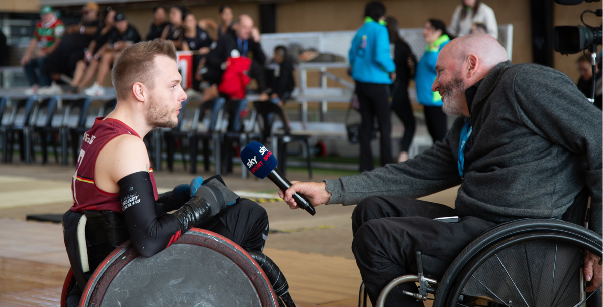 Jai interviews a wheelchair rugby player at a sports tournament.