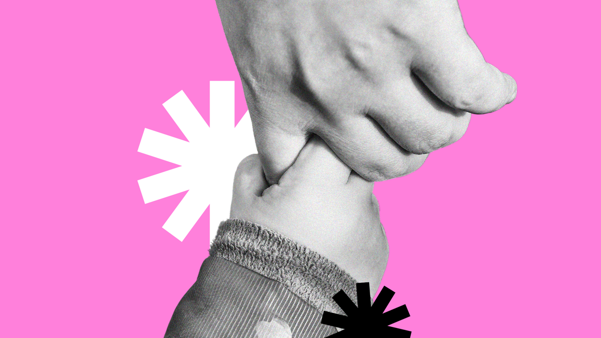 A black and white cropped image of an adult hand holds a baby's hand, on a pink background. Two tohuwhetū frame the two hands.