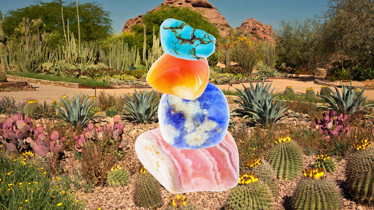 Four colourful stones are stacked up on top of each other, with a desert garden in the background.