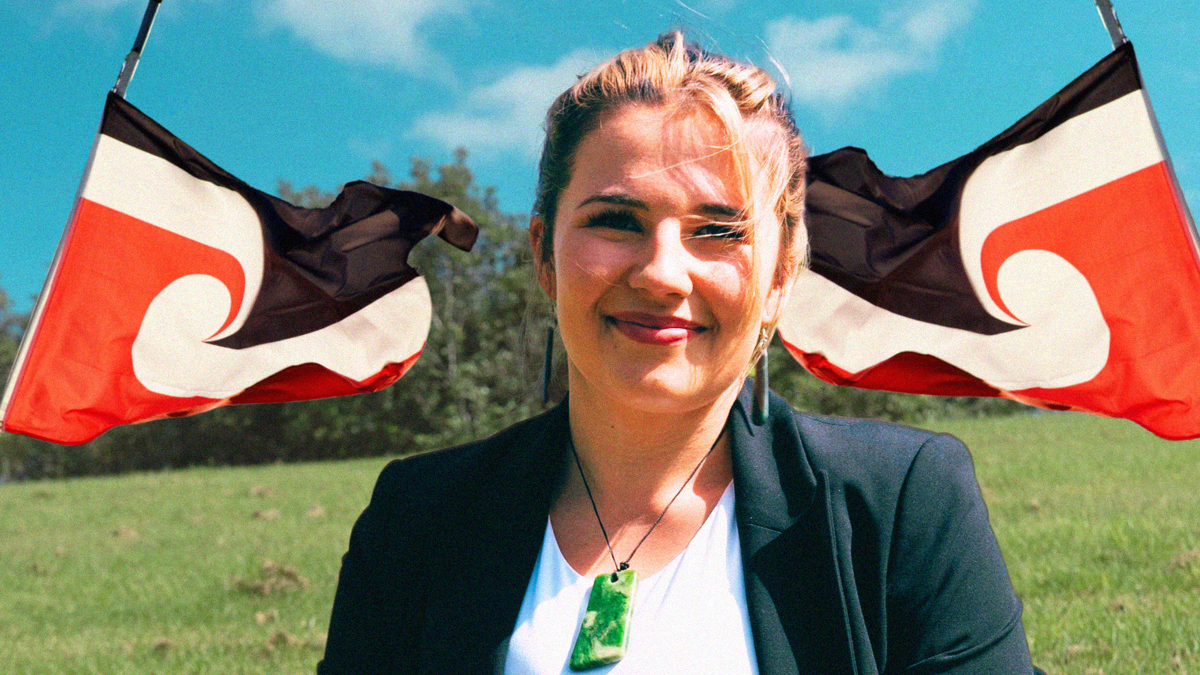 Tamara has blonde hair and wears a green ponamu. She is smiling pictured in a field and has the Tino Rangatiratanga flag behind her.