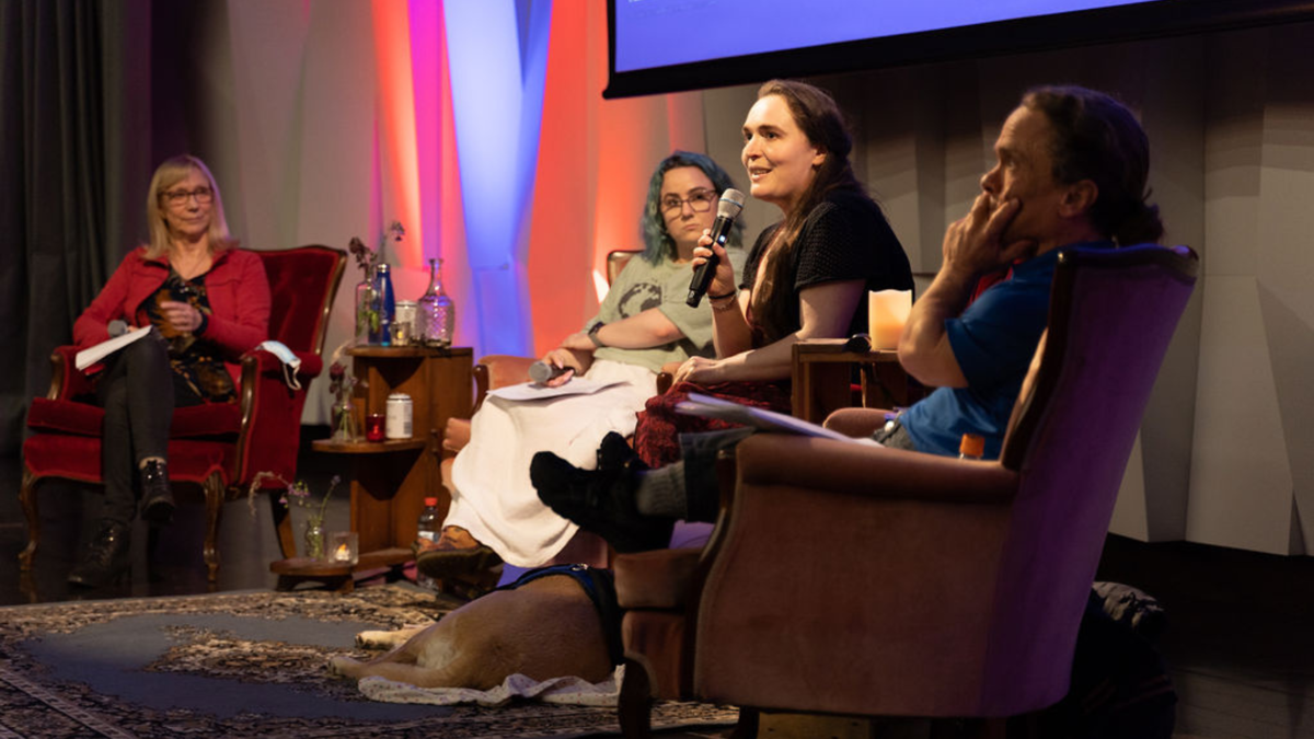 A panel of people sit on arm chairs on a stage at Verb Festival.