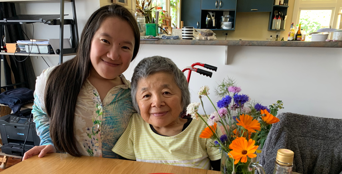 Umi and Yuho are pictured at a wooden table with bright, colourful flowers.