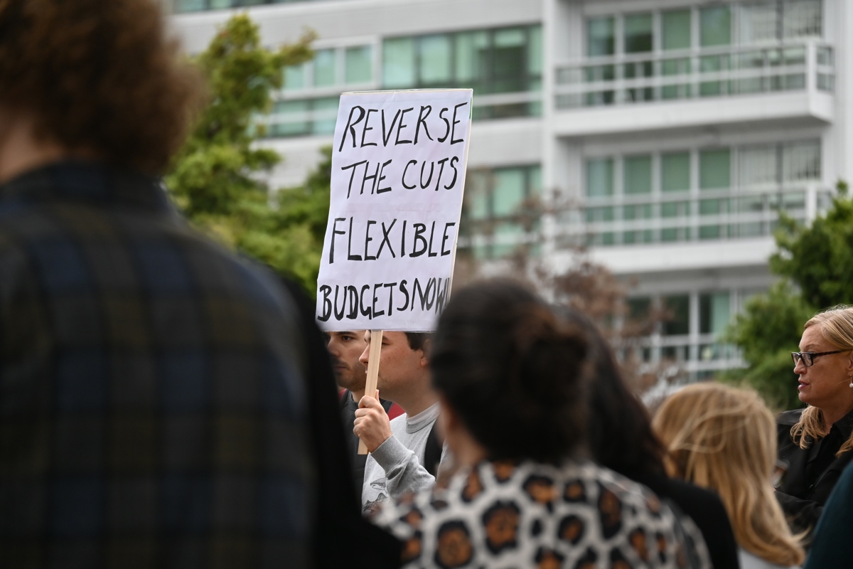 A crowd of people with a placard that reads: Reverse the cuts. Flexible budgets now.